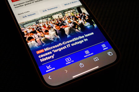 Paris, France - Jul 20, 2024: An iPhone displays a CNBC article about the Microsoft-CrowdStrike issue causing the largest IT outage in history, showing a crowd of people affected, with the screen highlighting various navigation optionsのeditorial素材