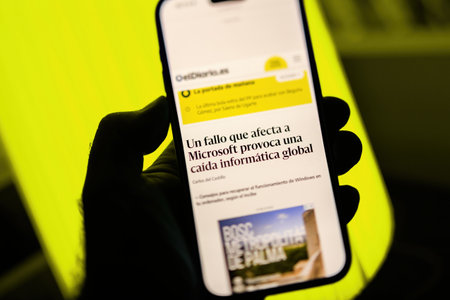 Paris, France - Jul 20, 2024: A smartphone screen displays a news article in Spanish about a Microsoft failure causing a global IT outage, set against a bright yellow backgroundのeditorial素材