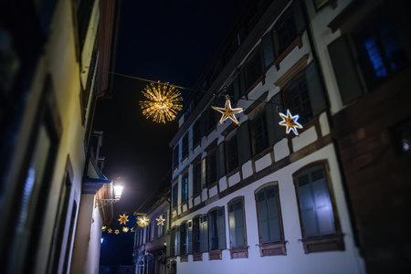A perspective view of multiple Christmas lights decorating stars above a street in Strasbourg, the capital of Christmas, with apartment buildings lining both sides, creating a festive and enchanting atmosphereの写真素材