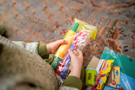 Paris, France - Mar 2, 2024: A child holding a package containing colorful Play-Doh tools, preparing...
