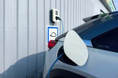 Electric car charging at a dedicated station with signage on the wall, featuring Electromobility and...