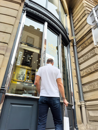 Strasbourg, France - Aug 23, 2024: Low-angle view of a man gazing at a luxury Swiss store selling ultra-expensive watches from Breitling, showcasing an opulent display in an upscale shopping areaのeditorial素材