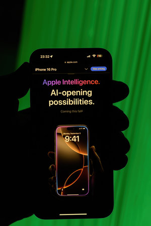Paris, France - Sep 8, 2024: Vertical shot of a male hand holding the iPhone 16 Pro Max against a green background, showcasing the Apple Intelligence: AI-Opening Possibilities slogan, highlighting upcoming AI-powered features in iOS for the iPhone 16 and のeditorial素材
