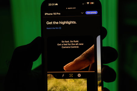 Paris, France - Sep 8, 2024: Vertical shot of a male hand holding the iPhone 16 Pro Max with a green background, showcasing the new camera button on the iPhone 16 Pro model, featuring zoom, focus, and other quick access shortcuts for enhanced photography のeditorial素材