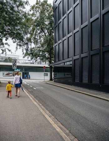 Basel, Switzerland - Sep 8, 2024: A mother and her son walk down a street in Basel, Switzerland, near a traditional building, capturing a peaceful urban family sceneのeditorial素材