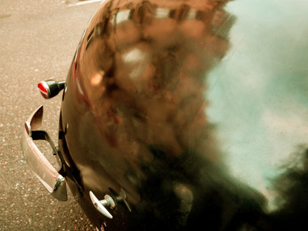 Close-up of a vintage cars rear, reflecting a blurred cityscape in its shiny surface, creating a nostalgic moodの写真素材