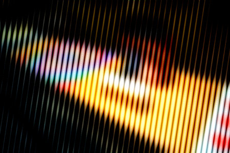 Abstract close-up of colorful light waves creating a vibrant, textured pattern with curved lines on a dark backgroundの写真素材