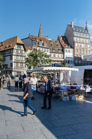 Strasbourg, France - Sep 20, 2024: Clothing market stall at Place Kleber in central Strasbourg, with seniors and adults shopping. A lively scene of fashion and local commerce in the bustling squareのeditorial素材