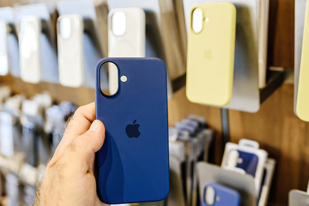 Paris, France - Sep 20, 2024: Male hand holding blue silicone case for iPhone 16 with multiple cases in the background, in an Apple storeのeditorial素材