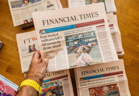 Paris, France - Aug 5, 2024: Hand holding Financial Times newspaper with headlines on Iran-backed militants killing 3 US troops in a drone attack and Gaza plea for aid amidst UNRWA allegations.のeditorial素材