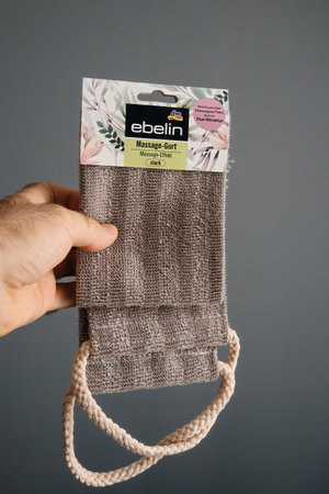 Berlin, Germany - Jul 9, 2020: A person holds a EBELIN DM massage cloth with a natural texture and rope handles, ideal for relaxation and self-care, against a neutral background.のeditorial素材