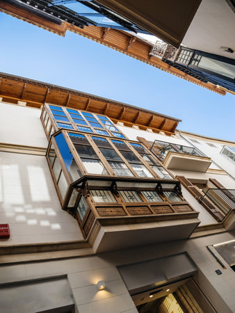 A view looking up at a traditional wooden balcony in Palma de Mallorca, highlighting intricate details and Mediterranean architectural style against a clear blue skyのeditorial素材