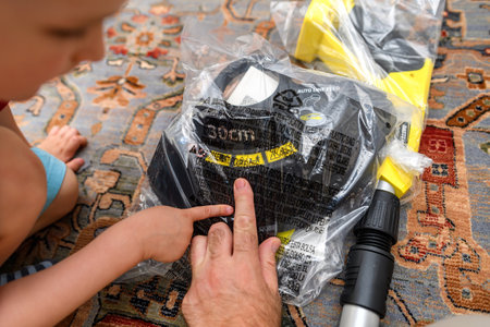 Paris, France - Jun 25, 2024: A child assists an adult in unpacking a Karcher tool from plastic packaging, pointing to warning labels while engaging in the home project setup.のeditorial素材