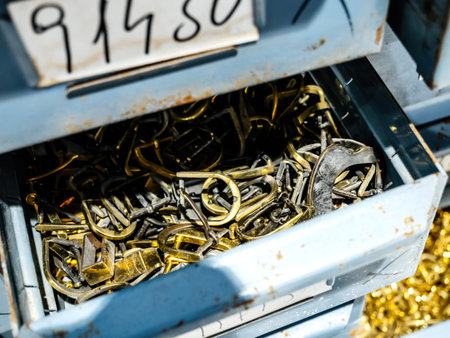 A drawer filled with metal buckles and various shoe parts, showcasing materials used in the footwear...
