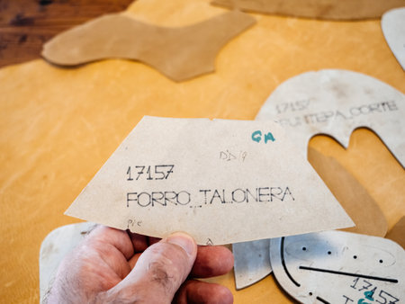 Palma, Spain - Jul 5, 2024: Hand holding a pattern piece labeled Forro Talonera, used for designing the heel lining in shoemaking, representing precision and craftsmanship in footwear productionのeditorial素材