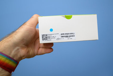 Paris, France - Dec 24, 2023: A hand holding a Phonak Charger Combi box, displaying product information, barcode, and QR code for a BTE hearing aid chargerのeditorial素材
