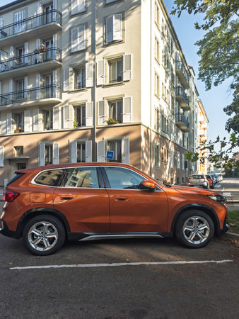 strasbourg, France - Sep 18, 2024: A sleek orange BMW iX1 electric car is parked in a quiet residential area, highlighting the modern electric vehicle against the backdrop of a traditional building on a sunny dayのeditorial素材