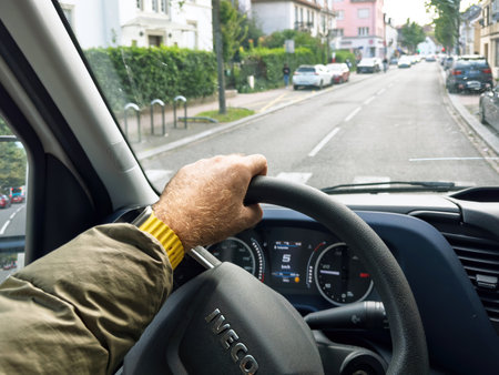 Paris, France - Sep 17, 2024: POV of a male driver s hand holding the steering wheel of an Iveco delivery truck on a narrow street in a French city, representing the delivery profession and urban navigationのeditorial素材