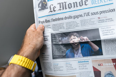 Paris, France - May 20, 2024: A person reads Le Monde newspaper featuring headlines on Netherlands: Far Right Wins, EU Under Pressure and an article on AI, Artificial Intelligence: Key Insights from the Sam Altman Case.のeditorial素材