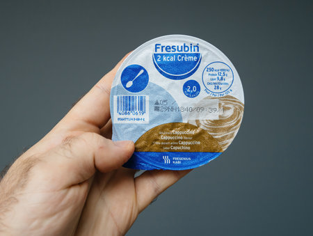 Paris, France - Mar 11, 2019: Close-up of a hand holding a Fresubin 2 kcal Creme cup in cappuccino flavor, showcasing the nutritional details on its packaging.のeditorial素材