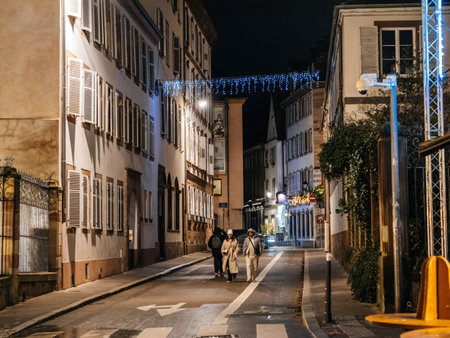 Strasbourg, France - Dec 23, 2024: Cozy street in Strasbourg illuminated by festive lights and monitored by a surveillance camera, capturing a peaceful nighttime sceneのeditorial素材