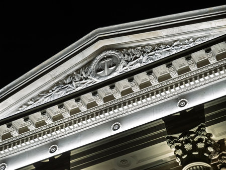 Close-up of a beautifully illuminated facade with detailed scales of justice, representing law and order, on a historic building at nightの写真素材