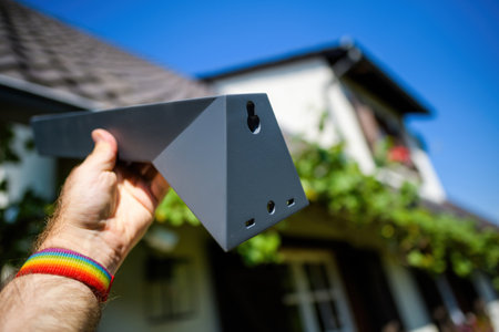 Frankfurt, Germany - Nov 3, 2023: Close-up of a hand holding a Starlink support bracket against a clear sky, preparing for satellite internet setup. Ideal for tech and installation visualsのeditorial素材