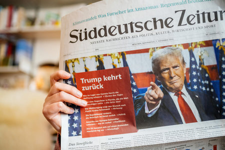 Paris, France - Nov 7, 2024: Close-up of woman reading Suddeutsche Zeitung in a cozy living room, with front-page headline on Donald Trump s election victory and his return to U.S. politicsのeditorial素材