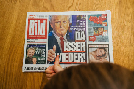 Paris, France - Nov 7, 2024: Curious toddler boy giving a thumbs-up to a German Bild newspaper with the headline Da Isser Wieder - There He Is Again featuring Donald Trumps return to the U.S. presidency.のeditorial素材