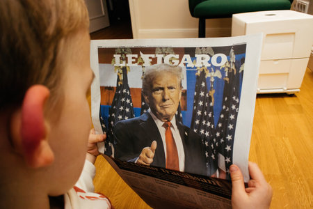 Paris, France - Nov 7, 2024: A child closely examines the cover of Le Figaro, featuring Donald Trump s election victory, reflecting international medias attention on the U.S. elections.のeditorial素材