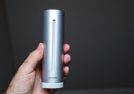 Paris, France - Nov 6, 2020: A person holds a sleek Netatmo weather station, showing the cylindrical, metallic design and advanced home technology in a closeup viewのeditorial素材