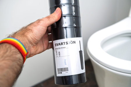Paris, France - Nov 6, 2020: Hand holding IKEA Svartsjon toilet brush package in black, ready for bathroom setup, with toilet visible in the backgroundのeditorial素材
