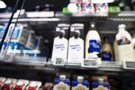 Defocused view of various milk bottles displayed in a refrigerated section of a Dutch supermarket,...