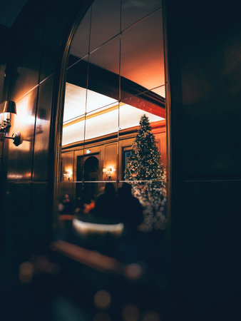 Baden, Baden - Germany - Dec 1, 2024: Elegant holiday interior reflected in a mirrored wall, showcasing a warmly lit Christmas tree and festive decor in a luxurious, dimly lit settingの写真素材