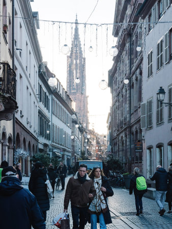 Strasbourg, France - Nov 29, 2024: Street view of Strasbourg during the Christmas market, featuring festive decorations, shoppers, and the iconic Strasbourg Cathedral in the background, creating a magical holiday atmosphereのeditorial素材