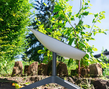 Frankfurt, Germany - Aug 8, 2024: Starlink satellite internet dish set in a lush garden surrounded by greenery and sunlightのeditorial素材