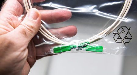 Close-up of a fiber optic cable with green connectors, displayed in a clear plastic bag with a...