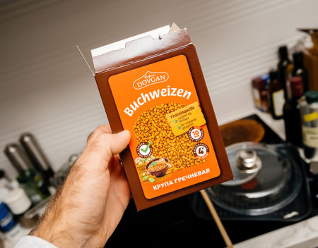 Paris, France - Oct 21, 2021: Hand holding a box of Dovgan Buchweizen buckwheat in a kitchen setting...