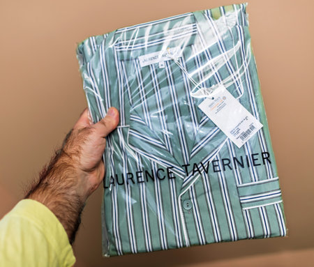 Laurence Tavernier striped pajamas in original packaging with tags, displayed against a beige background, emphasizing luxury sleepwear and French design quality - pov male handのeditorial素材