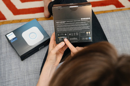 Paris, France - Aug 16, 2019: Close-up of a woman inspecting the back of the Philips Hue bulb packaging, highlighting technical specifications and features for smart lighting systemsのeditorial素材