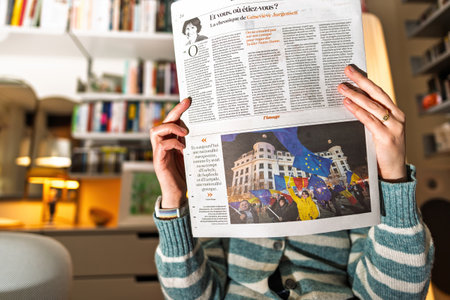 Paris, France - Dec 9, 2024: Person holding La Croix newspaper featuring an article on European identity with an image of protests, highlighting election-related unrest in Romaniaのeditorial素材