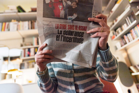 Paris, France - Dec 9, 2024: Person holding a newspaper with a headline about Syria in French, La...