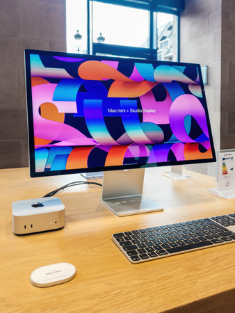Paris, France - Dec 10, 2024: The new Mac Mini featuring the M4 silicon chip paired with a vibrant Studio Display, keyboard, and accessories, showcased on a sleek wooden table in an Apple Store.のeditorial素材