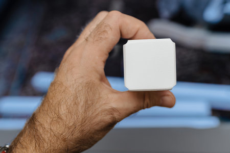A close-up view of a hand holding a white furniture part during the assembly process, with blurred components in the backgroundの写真素材