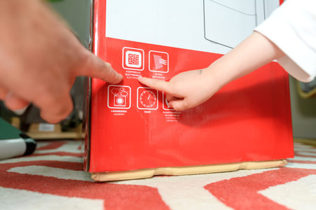 An older and an adult hand unbox a new dehumidifier, pointing to the electronic control icon on the generic packaging, showcasing the product's features and user-friendlinessの写真素材