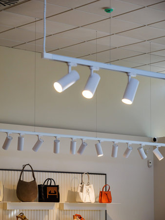 LED lights spotlight array illuminating a fashion clothing store, highlighting a display of diverse leather bags, creating an elegant and well-lit shopping environmentの写真素材