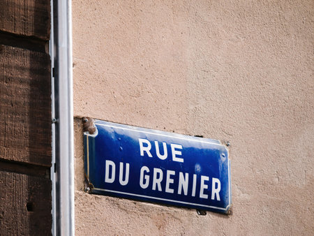 Vintage blue street sign is mounted on the side of a building, providing guidance to passersby navigating the city streets Rue du Grenierの写真素材