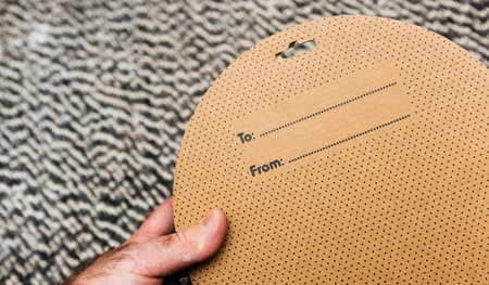 Hand holds cardboard round box featuring To and From label with space to write names, perfect for...