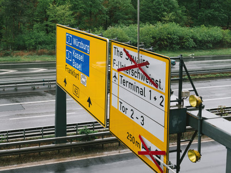 A bright yellow directional sign mounted on a pole by the side of a road, showing directions to...