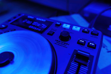 A DJ mixing deck controller with a blue color cast, emphasizing its track search and loop functionsの写真素材